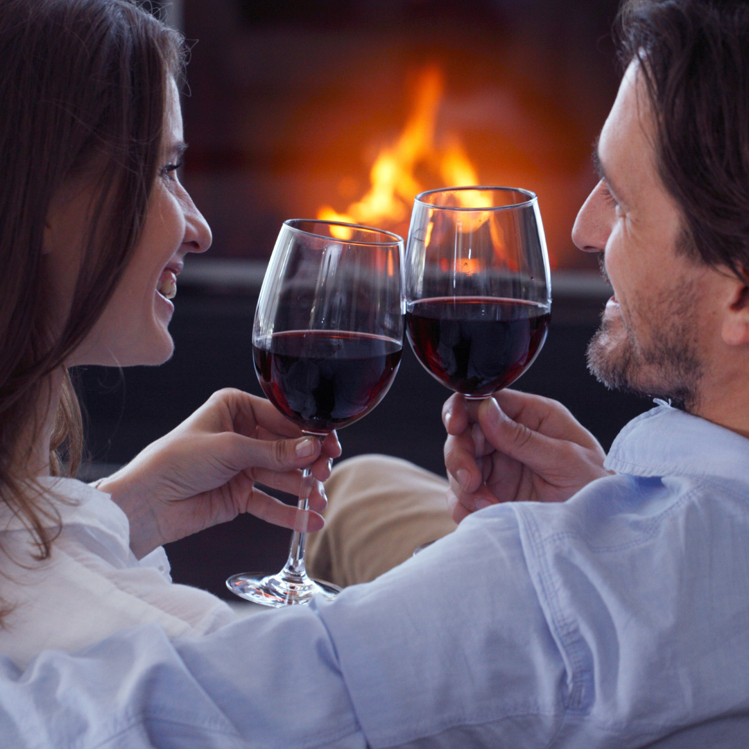 a couple enjoying a glass of wine by the fireplace